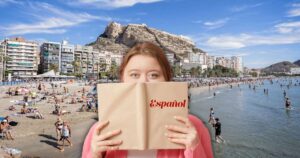 Een vrouw met een leerboek Spaans in de handen aan een Spaans strand