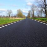 Een versgelegd asfaltwegdek in een landelijk landschap